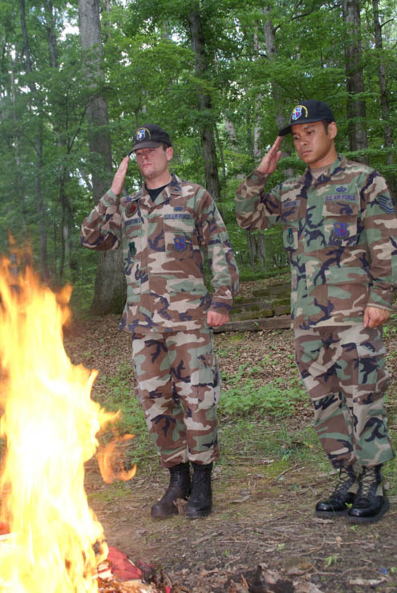 From left, 1st Lieutenant Robert Thornton and Tech. Sgt. John Bankston, with AEDC’s Air Force Honor Guard, salute an American flag while it burns during a flag retirement ceremony held at Camp Arrowhead, a Boy Scout camp on the base near Woods Reservoir. (Photo by Philip Lorenz III) 