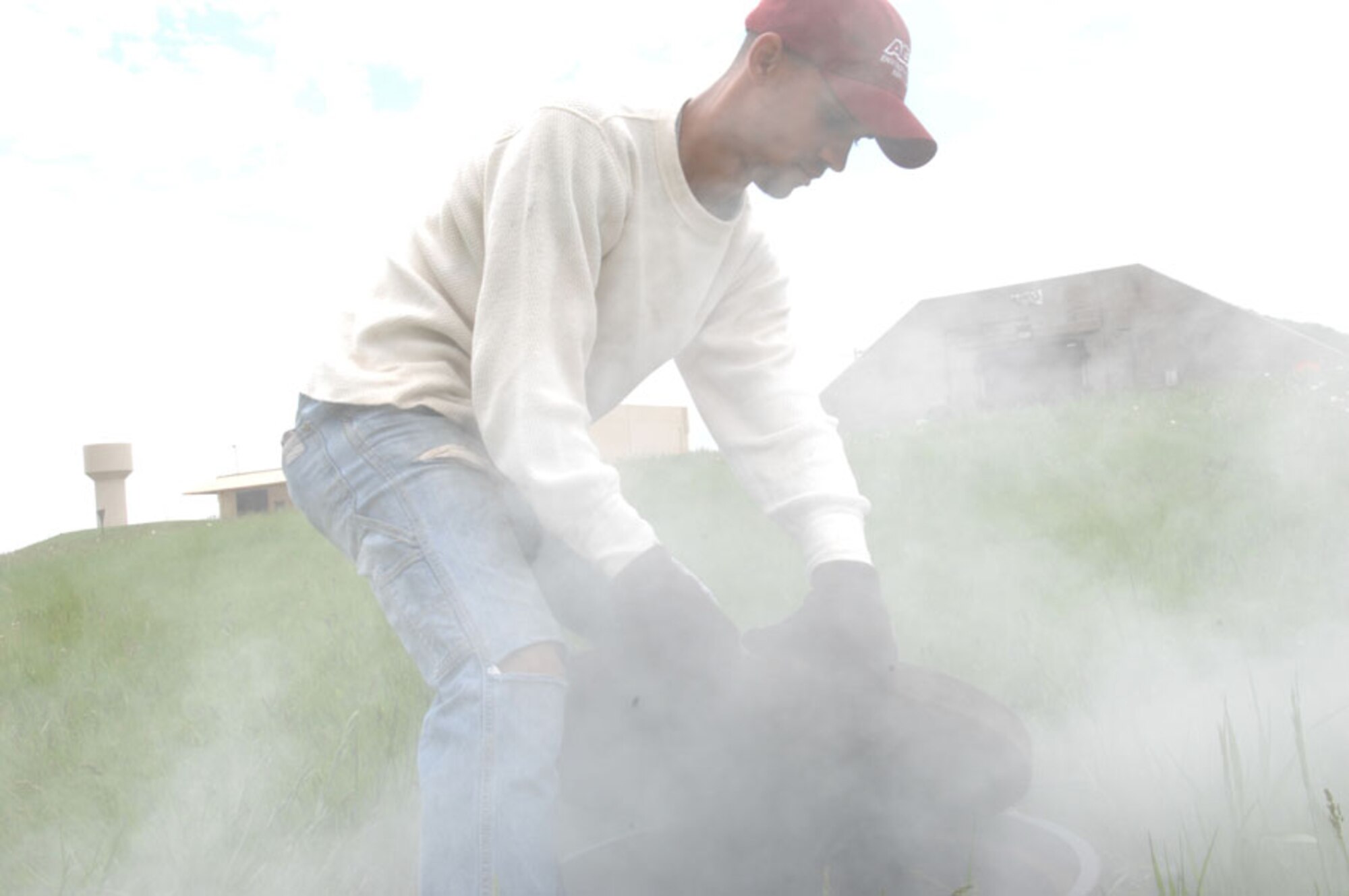 Jason Harris, American Digital Services sewer line smoke tester, works through a cloud of smoke as he lifts a manhole on Ellsworth Air Force Base, S.D., June 6, 2008. This smoke blower produces 2500 pounds of pressure per square inch and  pushes non toxic, odorless smoke into the manhole identifies where ground water is leaking out of the underground piping system. (U.S. Air Force photo/Airman 1st Class Adam Grant)