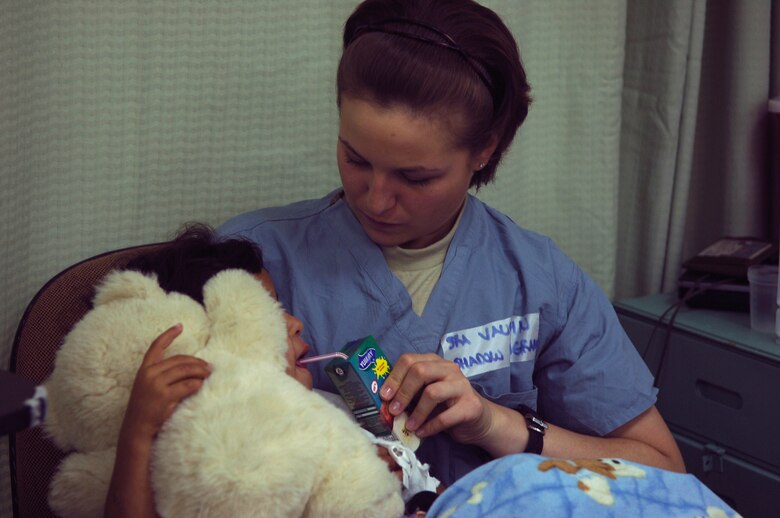 BALAD AIR BASE, Iraq -- Senior Airman Nicole Vaughn, assigned to the 23rd Expeditionary Fighter Squadron, spends time with a young Iraqi girl, a patient at the Air Force Theater Hospital here, as part of a job swap program. The program allows Airmen outside of the medical career field to spend a day shadowing hospital personnel. Airman Vaughn is deployed from Spangdahlem Air Base, Germany. (U.S. Air Force photo /Staff Sgt. Mareshah Haynes)