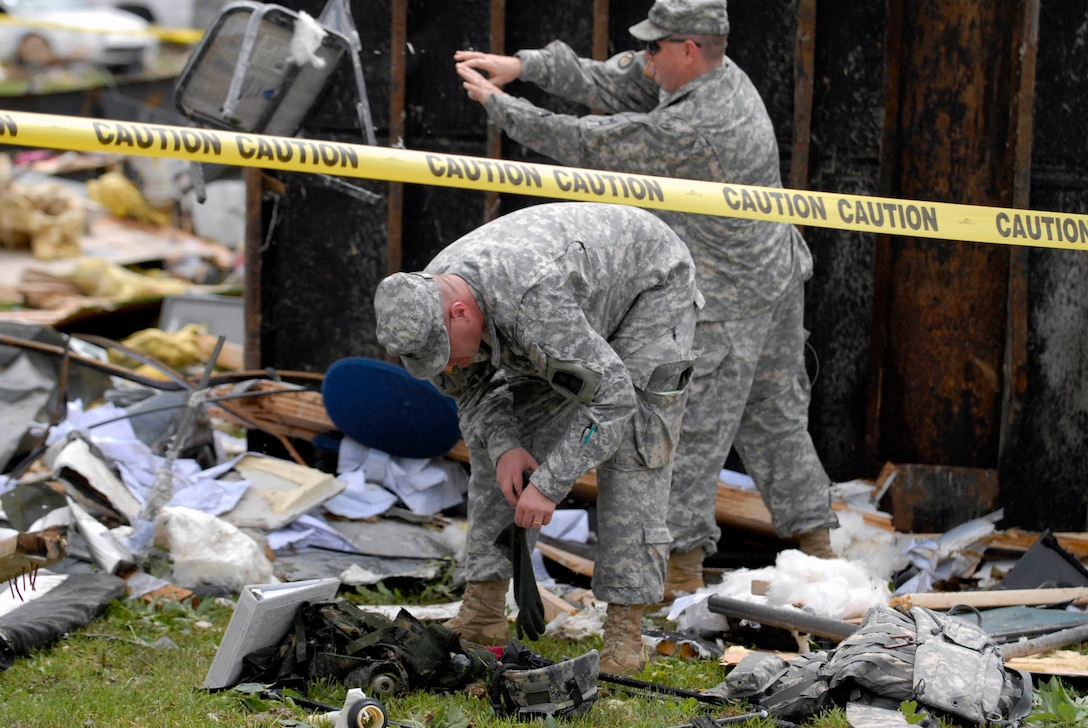 U.S. soldiers go through debris after an F2 tornado ripped through the installation, June 3, 2008, at 9:40 p.m. No injuries were reported, but more than 40 buildings and numerous military and civilian vehicles were destroyed during the storm. The soldiers are assigned to the 205th Infantry Brigade.