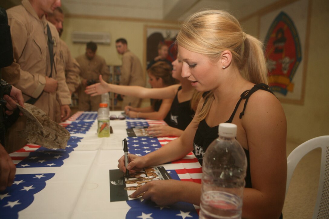 Signing autographs for service members aboard Camp Korean Village, Iraq, Laura Jenkins, 23, a cheerleader from Poughkeepsie, N.Y., with the Philadelphia Eagle cheerleading squad, converses and learns about the lives of the troops during a visit at the camp, June 6.  The greeting was part of a tour around Iraq for the ladies to meet and greet service members fighting in support of Operation Iraqi Freedom. During the event, the cheerleaders took pictures with Marines and sailors, signed autographs and thanked them for their service to the nation.