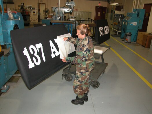 Staff Sgt. Sue Hathaway, a structural repair and corrosion control technician with the Air Force Reserve's 507th Air Refueling Wing, peels away transfer paper backing while applying new lettering to a KC-135 ruddervator.  
  As a result of the 2005 BRAC process, the 507th Air Refueling Wing became the first Air Force Reserve wing to become host to an Air National Guard wing.  
  The Oklahoma Air National Guard's 137th Air Refueling Wing began flying associate missions here at Tinker Air Force base earlier this year.   Assigning dual wing identification on the KC-135 ruddervator is part of local processes to provide identification and partnership parity.  
