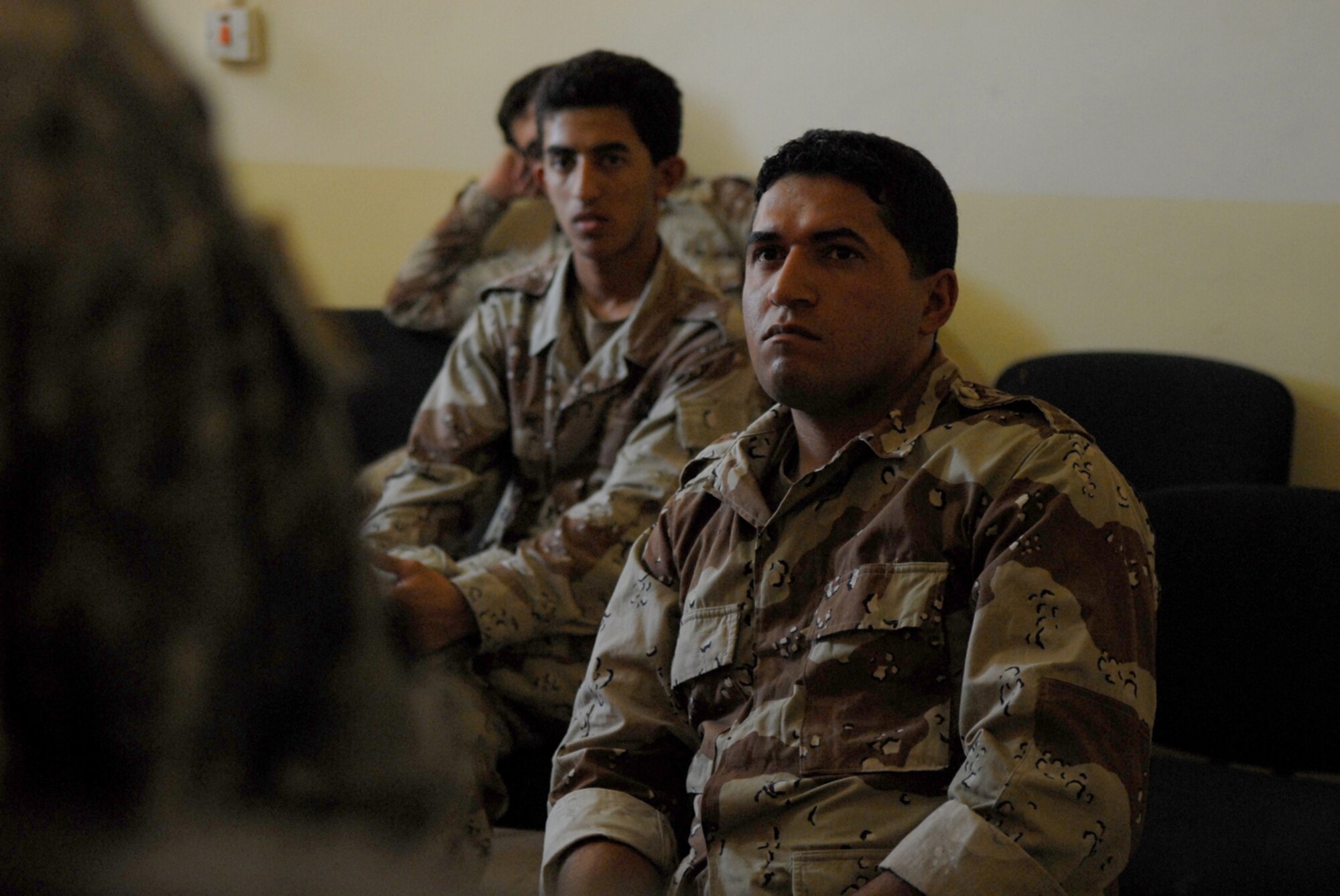 CAMP TAJI, Iraq -- Iraqi air force aerial gunner trainees listen in as an interpreter relays the message of the instructor at Camp Taji, May 29. A discussion with the trainees can be challenging due to language barriers and cultural differences. With the assistance of a translator and hand gestures this obstacle is overcome to ensure the correct message is relayed and understood by the trainees. (U.S. Air Force photo/ Senior Airman Julianne Showalter)
