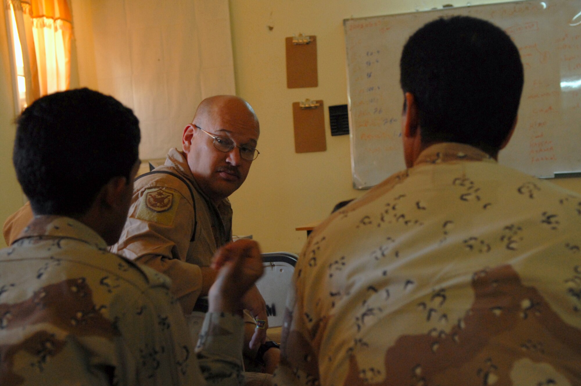 CAMP TAJI, Iraq -- Master Sgt. Bradley Martens, 770th Air Expeditionary Advisory Squadron lead aerial gunner training instructor, speaks with Iraqi air force trainees about procedures before a mission over Camp Taji, May 29. A discussion with the trainees can be a challenge due to language barriers and cultural differences. With the assistance of a translator and hand gestures this obstacle is overcome to ensure accurate messages are relayed and received. Sergeant Martens is deployed from Hurlburt Field, Fla. (U.S. Air Force photo/ Senior Airman Julianne Showalter)