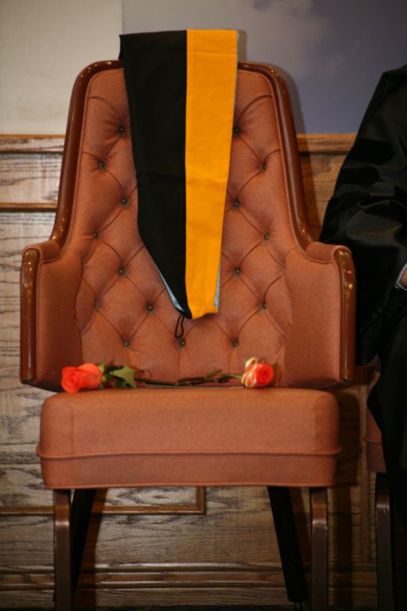An chair draped with a graduation hood holds two roses in honor of the late Maj. Brad Funk, an instructor pilot at the 80th Flying Training Wing who was killed during a training mission May 1 at Sheppard Air Force Base, Texas. The open-bloom rose on the left signifies the accomplishments of Major Funk during his lifetime, while the closed-bloom rose symbolizes what he had yet to accomplish. Embry-Riddle Aeronautical University posthumously awarded Major Funk a master's degree in aeronautical engineering. (U.S. Air Force photo/Lt. Col. Ternell Washington)
