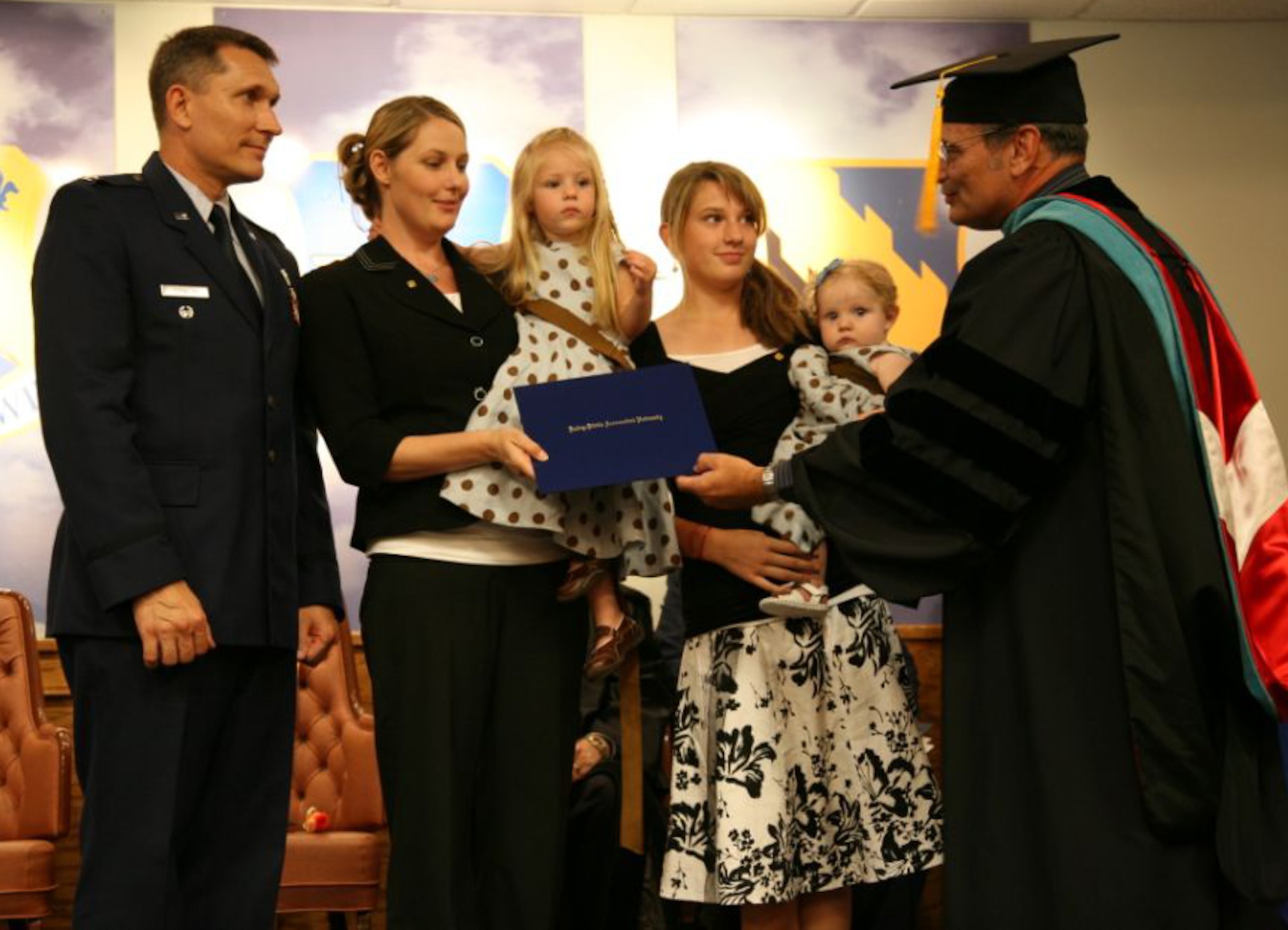 Jennifer Funk, second from the left, accepts her late husband Maj. Brad Funk's master's degree in aeronautical science June 6 from Dr. Bruce Rothwell, central region dean of academic affairs for Embry-Riddle Aeronautical University, during a graduation ceremony at Sheppard Air Force Base, Texas. Major Funk, killed during a training mission May 1 here, was awarded his degree posthumously. Also pictured, from left to right, is Col. Daniel Torweihe, 80th Flying Training Wing vice commander, Sophia Funk, Tyler Funk and Addison Funk. (U.S. Air Force photo/Lt. Col. Ternell Washington)