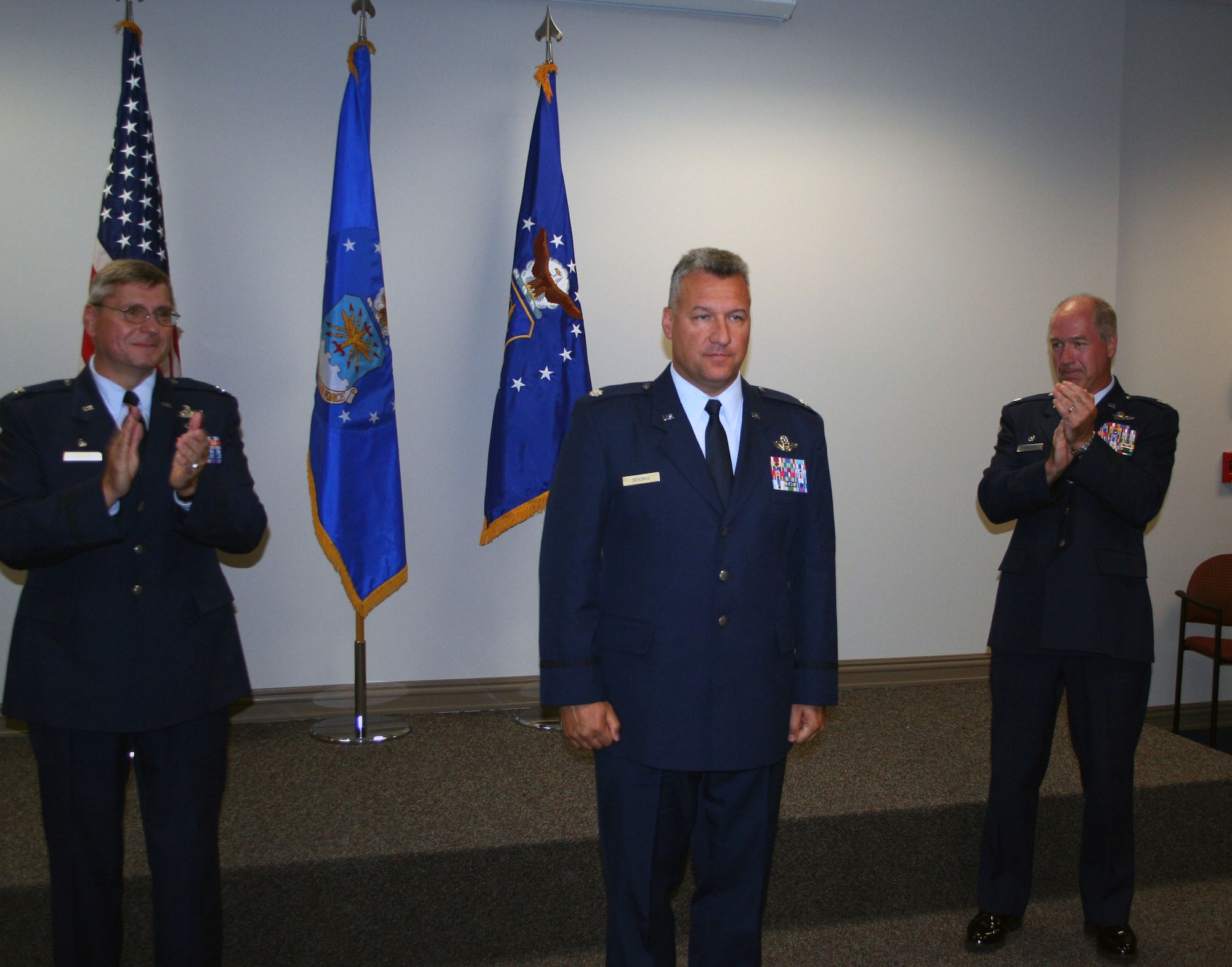 WRIGHT-PATTERSON AFB, Ohio - Lt. Col. Mike Bending addresses the audience after he assumes command of the 89th Airlift Squadron, a squadron within the 445th Airlift Wing.  Col. Roger Gallet (left), 445th Operations Group commander, and Lt. Col. Timothy Baldwin (right), outgoing 89th Airlift Squadron commander, clap as Col. Bending makes his first speech as commander. (U.S. Air Force photo/Staff Sgt. Martin Moleski)