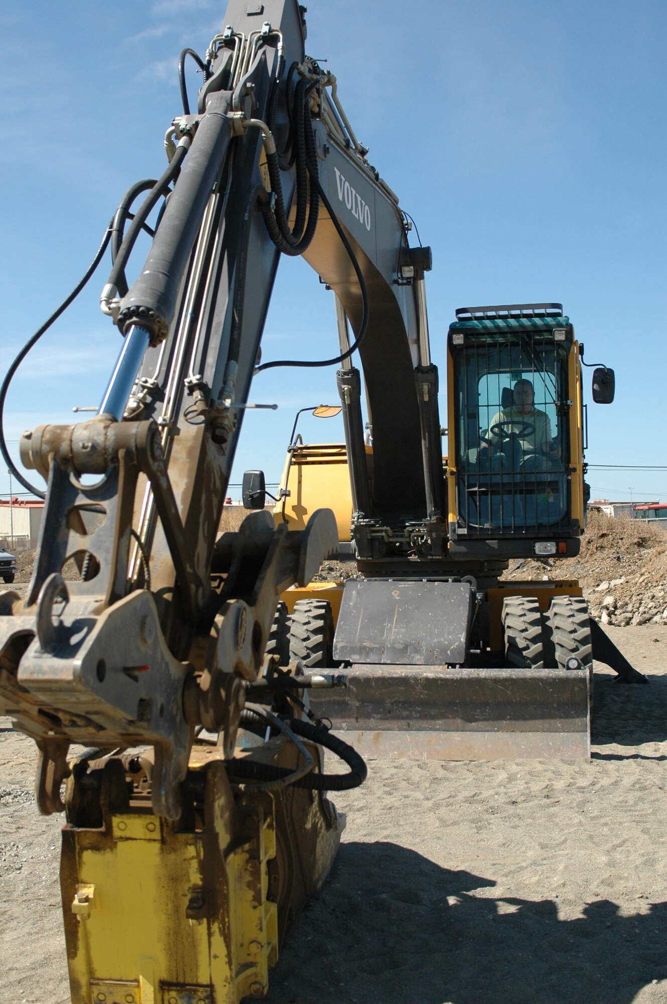 Airman 1st Class Hilario, 60th Civil Engineering Squadron heavy equipment opertor lines up the boom on a rubber-tire excavator in order to connect a rock crusher attachment. (U.S. Air Force photo/Senior Airman Shaun Emery)
 
