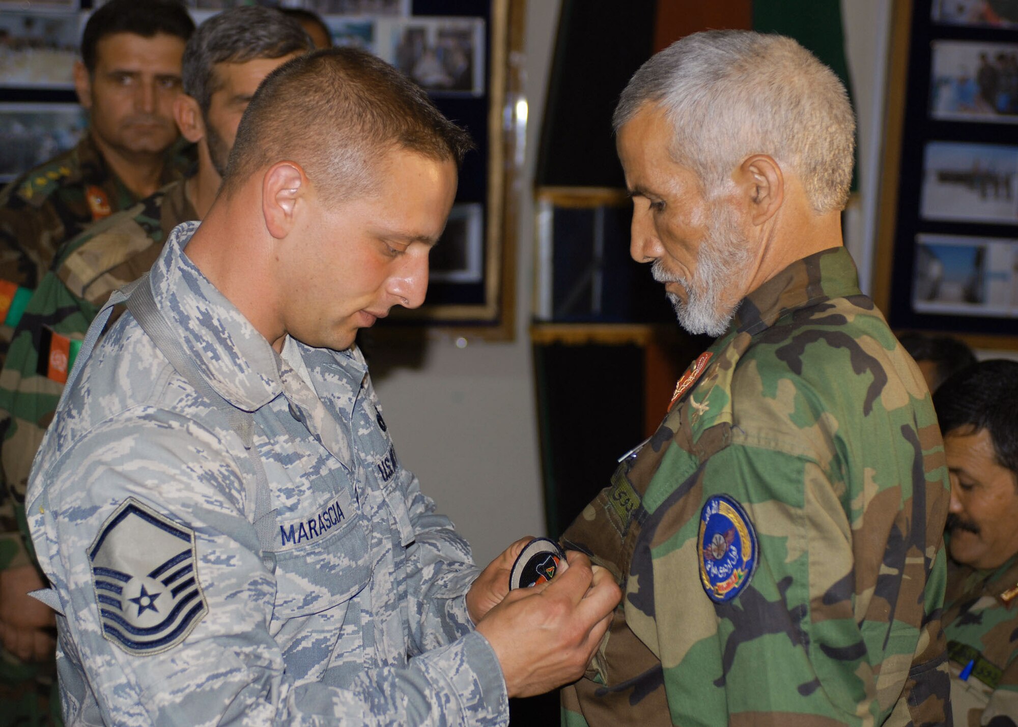 Master Sgt. Michael Marascia pins a firefighting badge on 48-year-old Razzuddin at a graduation ceremony of the first Afghan National Army Air Corps Firefighting Class May 29 Kabul, Afghanistan. The 11 graduates will be assigned to the new ANAAC North Side Cantonment at the Kabul International Airport, scheduled to open in October 2008. (U.S. Navy photo/Petty Officer 1st Class Douglas Mappin)