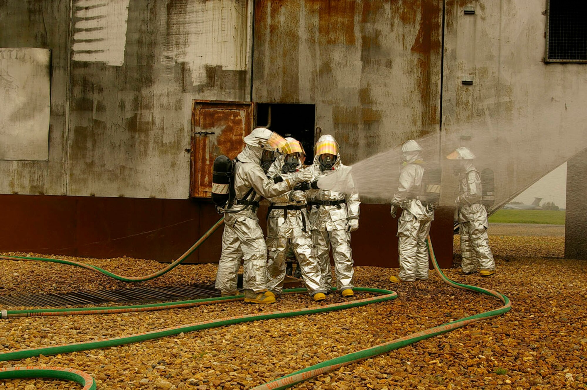 Karen Abeyasekere, second left, 100th ARW Public Affairs, Capt. Kelly Bolen, center, 100th ARW Inspector General's Office, and Senior Airman Teresa Hawkins, far right, get a quick briefing on how to work the hose from two of RAF Mildenhall's firefighters. (U.S. Air Force photo by Master Sgt. Rick Henderson)