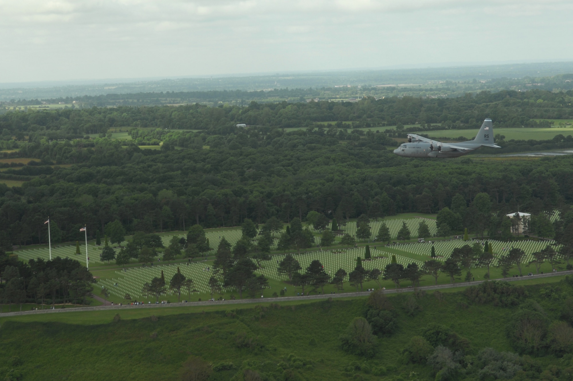 Airmen from the 37th Airlift Squadron fly past the Normandy American Cemetery and Memorial, Omaha in a C-130 Hercules June 6. The fly-by was done to commemorate those who were lost 64 years ago during the Normandy invasion, D-day. Photo by Airman 1st Class Amber Bressler*