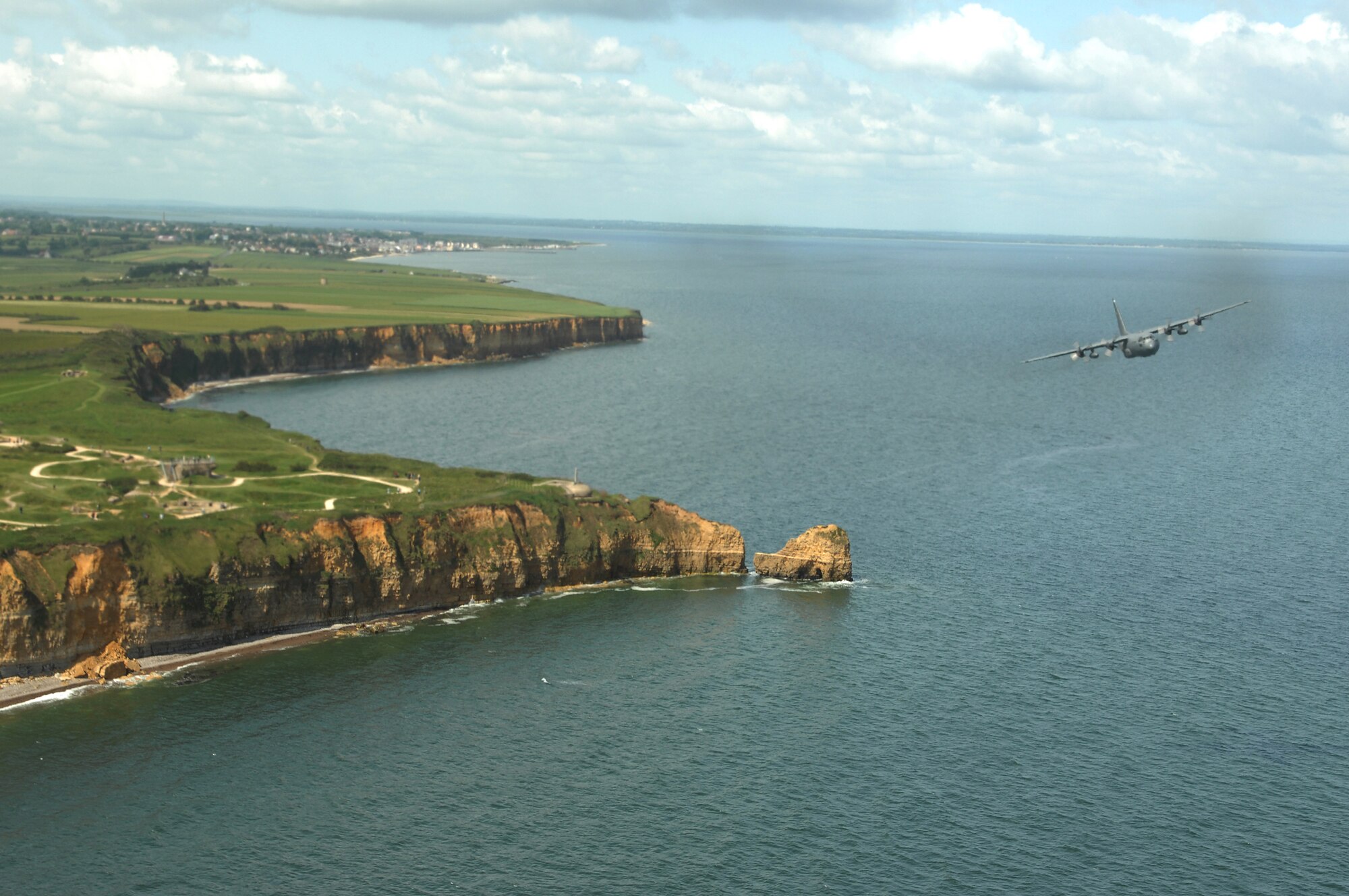 Airmen from the 37th Airlift Squadron fly past Point du Hoc, France in a C-130 Hercules June 6.  The fy-by was done to commemorate those who were lost 64 years ago during the Normandy invasion, D-day.  Photo by Airman 1st Class Amber Bressler*
