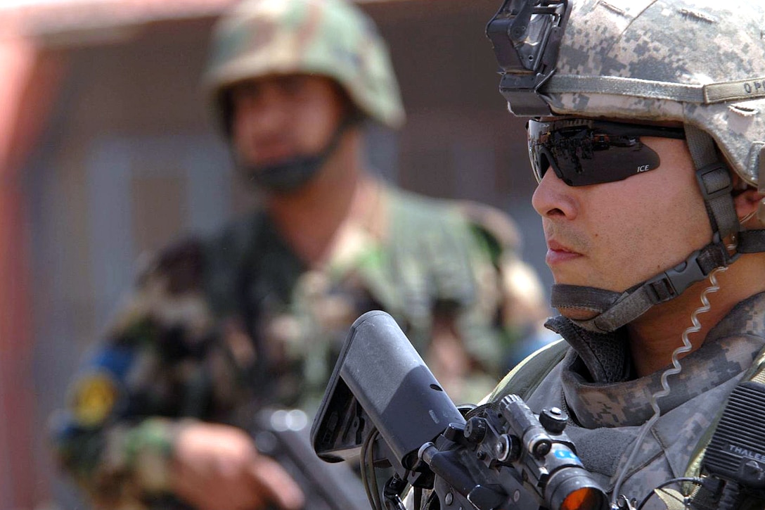 U.S. Army Capt. Eric Oksenvaag and an Iraqi soldier provide security for Iraqi Deputy Prime Minister Barham Salih and U.S. Army Multi-National Force - Iraq Commander Gen. David H. Petraeus as they walk through a Sadr City neighborhood in Baghdad, June 4, 2008. 