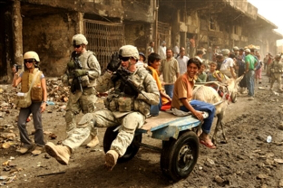 A U.S. Army soldier gets a lift from an Iraqi boy and his mule on Route Douglas in the Jamilla Market in the Sadr City district of Baghdad, June 9, 2008. The soldier is assigned to the 6th Infantry Division, which is helping to clean up the market area to restore commerce.