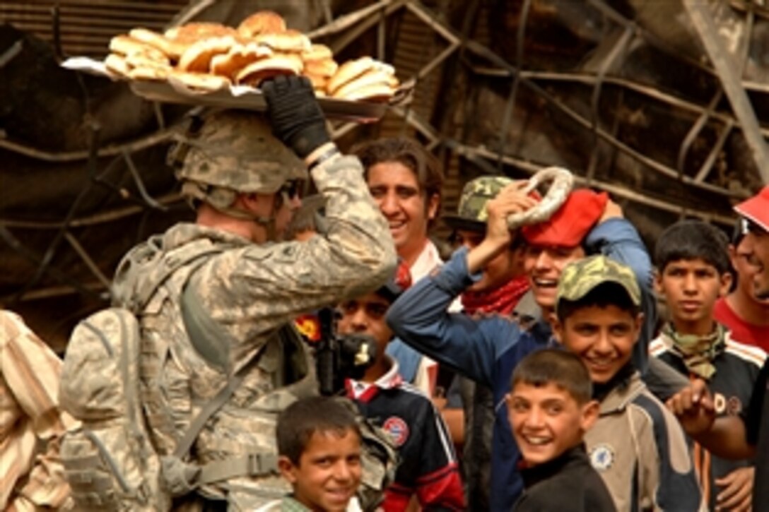 A group of Iraqi children look on as a U.S. soldier practices balancing a plate of bread on his head in the Jameela market area of the Sadr City district of Baghdad, Iraq, May 31, 2008. The soldier is assigned to the 6th Infantry Division's 1st Brigade Combat Team, which is attached to Task Force Regulars.