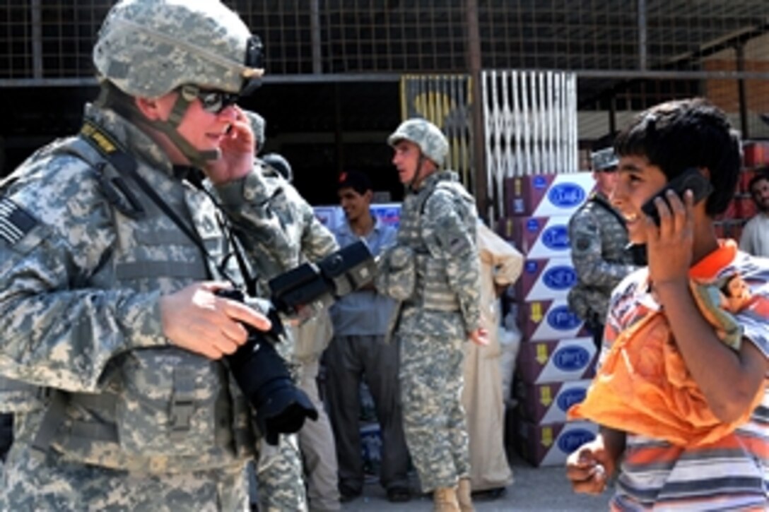 U.S. Army Staff Sgt. Lorie Jewell, Multinational Force Iraq photographer, helps an Iraqi boy practice his English phone etiquette in the Sadr City district of Baghdad, Iraq, June 4, 2008. 