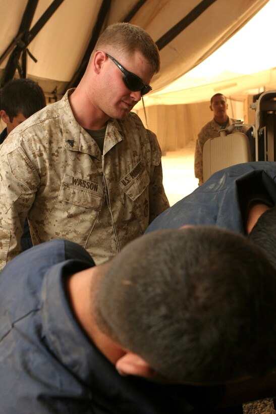 Cpl. Derek J. Wasson, a floor chief with Maintenance Company, Combat Logistics Battalion 1, 1st Marine Logistics Group watches over Iraqi policeman during the humvee maintenance course. The 4 day course taught local IPâ??s the skills necessary to fix and maintain their own humvees thus lessening the need for coalition mechanicsâ?? help.::r::::n::