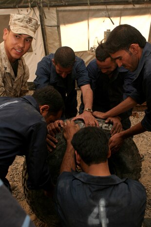 Cpl. Richard Realyvasquez, the tire shop non-commissioned officer in charge for Maintenance Company, Combat Logistics Battalion 1, 1st Marine Logistics Group, demonstrates the correct way to remove a wheel rim from a tire during the humvee maintenance course. The course taught local IPs the skills necessary to fix and maintain their own humvees.::r::::n::