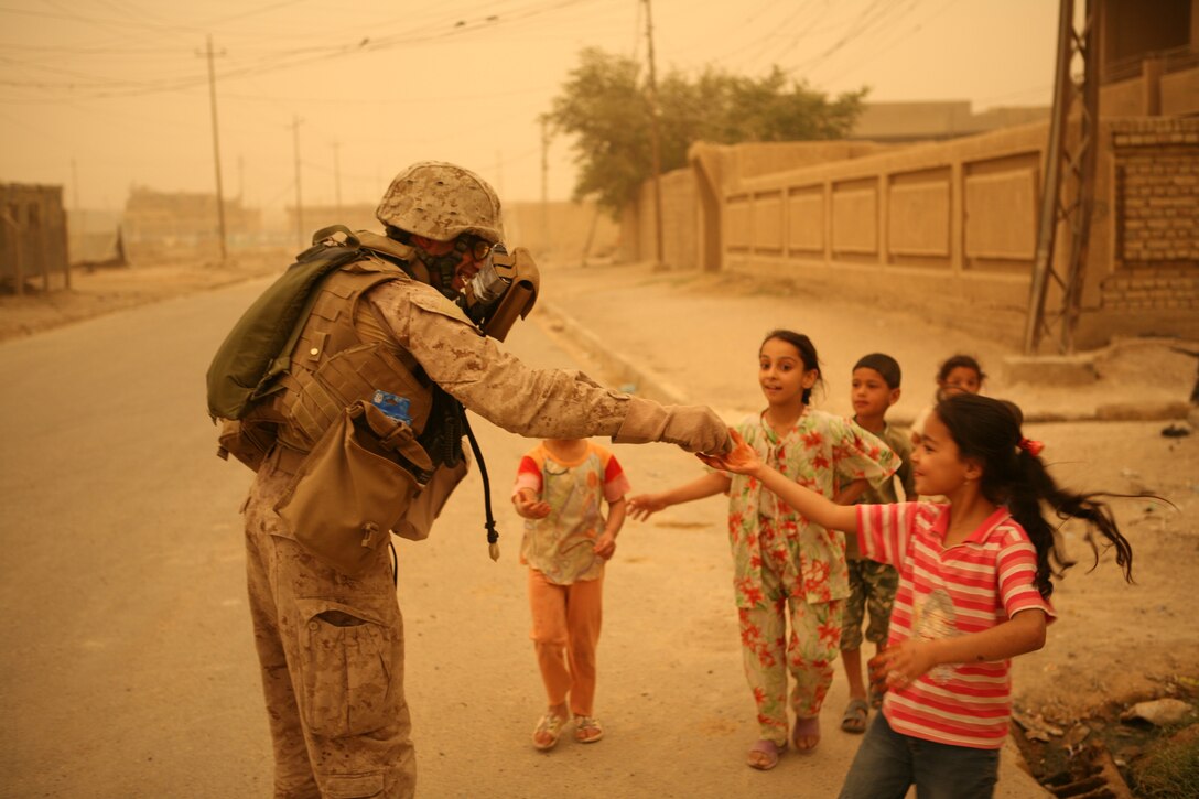 "Mylo" an interpretor with Company B, Iraqi Transition Team 8, Regimental Combat Team 1, passes out candy and school supplies to Iraqi childeren during a patrol in Fallujah June 9. (Official Marine Corps photo by Cpl. Chris T. Mann)::r::::n::