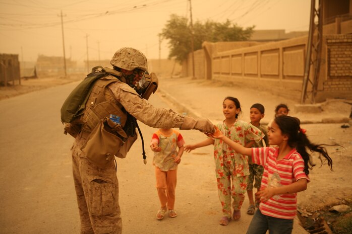 "Mylo" an interpretor with Company B, Iraqi Transition Team 8, Regimental Combat Team 1, passes out candy and school supplies to Iraqi childeren during a patrol in Fallujah June 9. (Official Marine Corps photo by Cpl. Chris T. Mann)::r::::n::