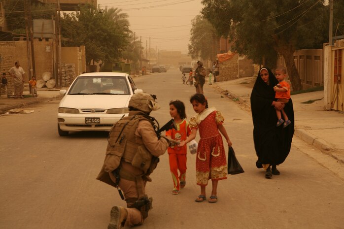 Cpl. Jonathan C. Austin, communications chief and convoy commander with Company B, Iraqi Transition Team 8, Regimental Combat Team 1, hands out candy to Iraqi childeren during a patrol through Fallujah June 9. Austin, a Lincolnton, N.C. native, works with the transition team to check up on local Fallujah citizens. (Official Marine Corps photo by Cpl. Chris T. Mann)::r::::n::