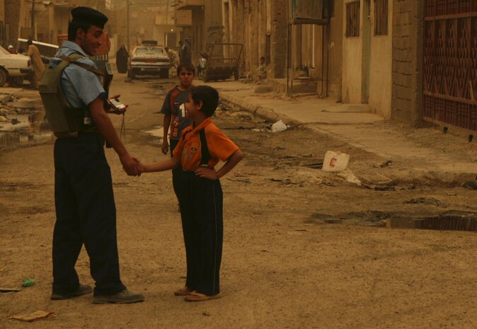 An Iraqi Policeman receives a welcoming response from a young citizen on the recovering streets of Ramadi during a patrol near the souk June 9. One of the most visible changes in the city has been the constant effort to remove rubbish from the streets. "A real big problem in the city right now is trash," said Gunnery Sgt. John Cuoco, a team leader with 11th Marine Regiment, an artillery battery currently serving as a provisional civil affairs group in direct support of 1st Battalion, 9th Marines. "(Iraqi and Coalition forces) are making efforts to have the locals use the dumpsters properly. We are doing several campaigns to increase literal awareness. We recently gave informational products to put in every classroom in Ramadi to explain to the children why it's important for them not to litter and use the dumpsters. We're focusing on the children because they do most of the heavy-lifting in Iraq, so if a household empties the trash it's usually a child bringing the trash out."