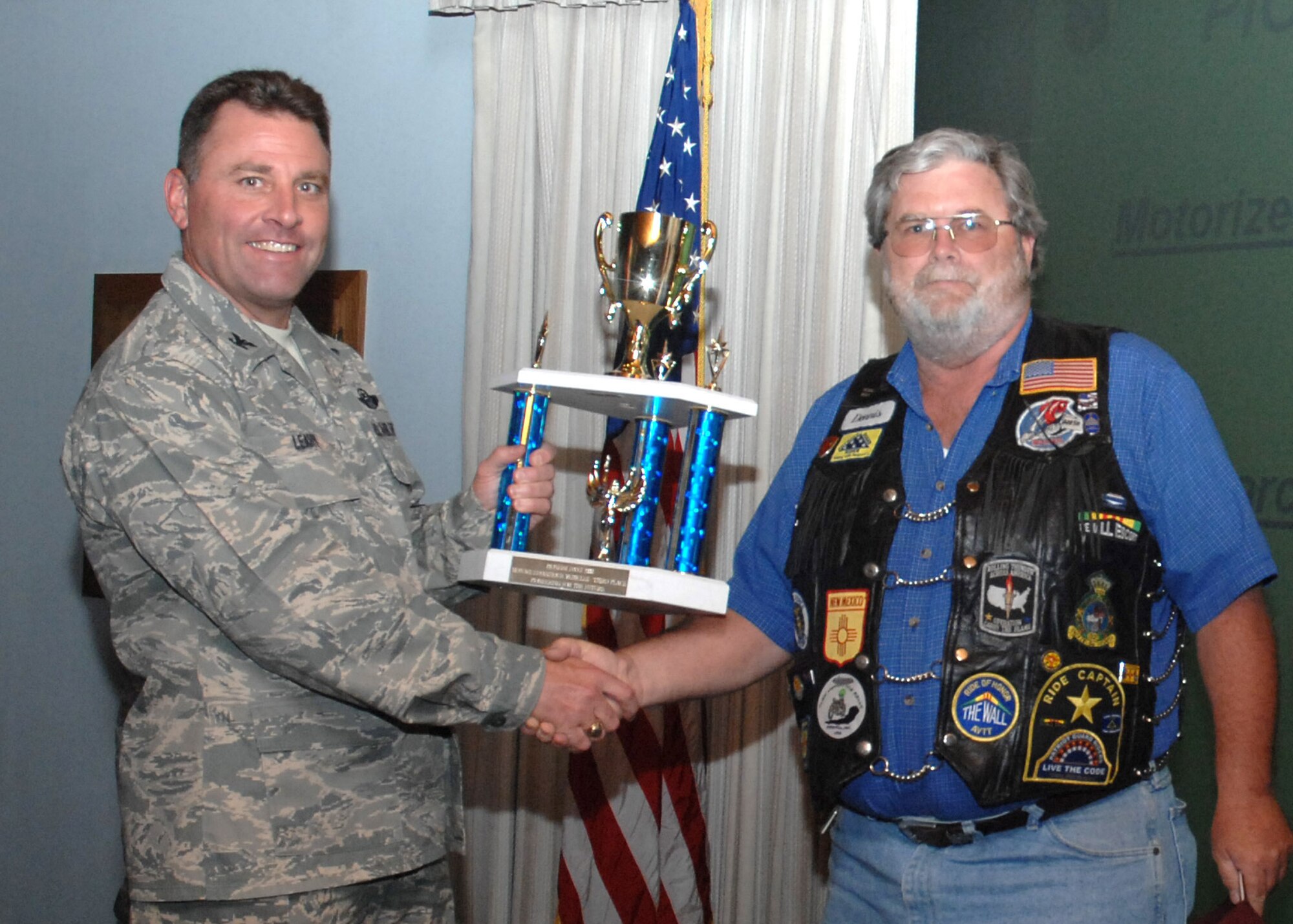 CANNON AIR FORCE BASE, N.M. -- Dennis Chalker, 27th Special Operations Civil Engineer Squadron, receives the Motorized/Antique Vehicles third-place trophy on behalf of the 27th Special Operations Wing Motorcycle Riders Group group presented by Col. Timothy Leahy, 27th SOW commander, June 10.The motorcyclists participated in the 38th annual Pioneer Days Parade in downtown Clovis, N.M., June 7. (U.S. Air Force photo/Airman 1st Class Evelyn Chavez)