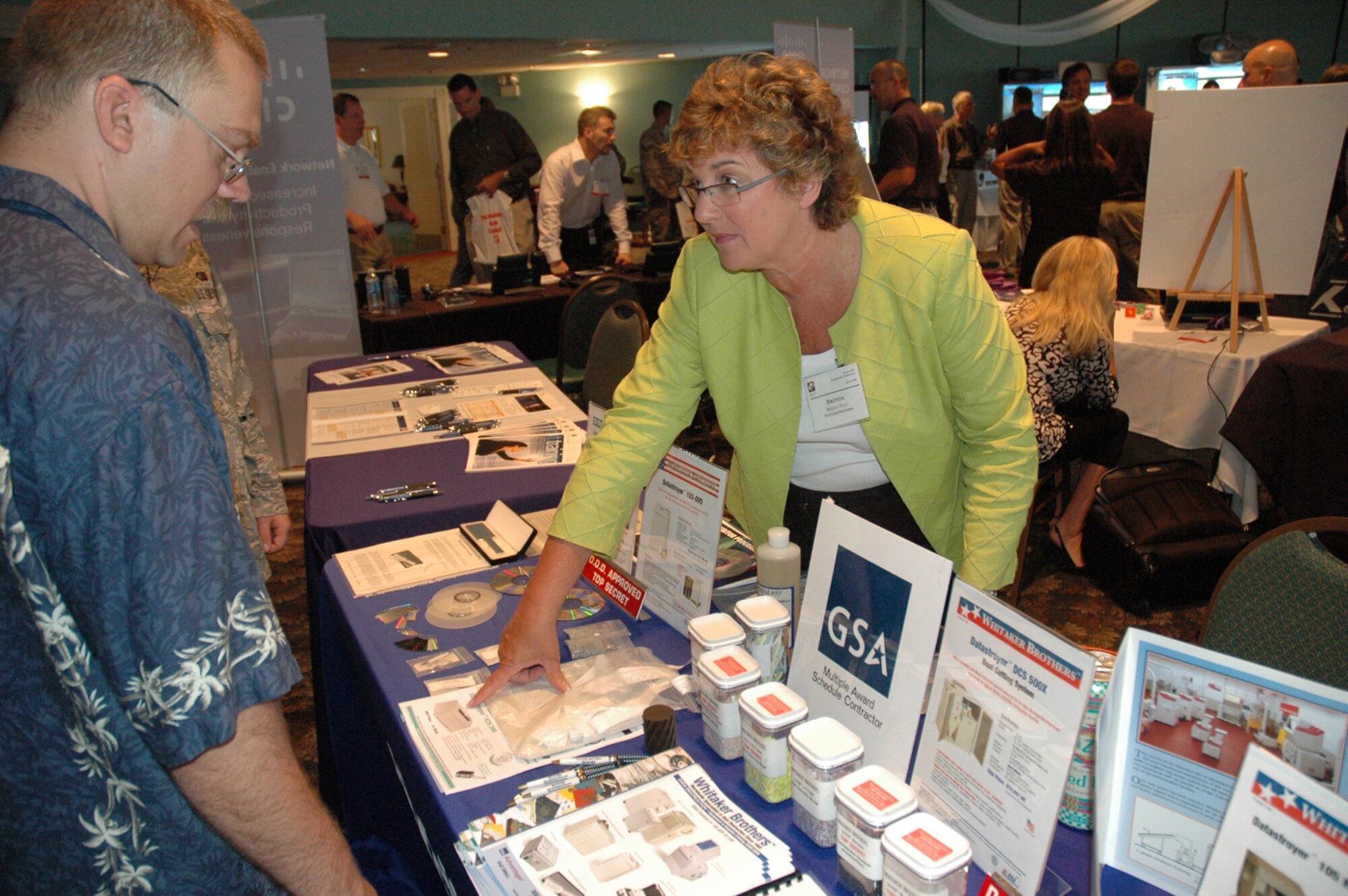 EGLIN AIR FORCE BASE -- Brenda Palo, Whitaker Brothers federal account manager, showcases one of her company's data destruction products to Staff Sgt. Chris Kodya, 96th Communication Squadron, at the Technology Expo in the Officer's Club June 6. The Expo is an annual event where different companies display the advances in their products and ideas.