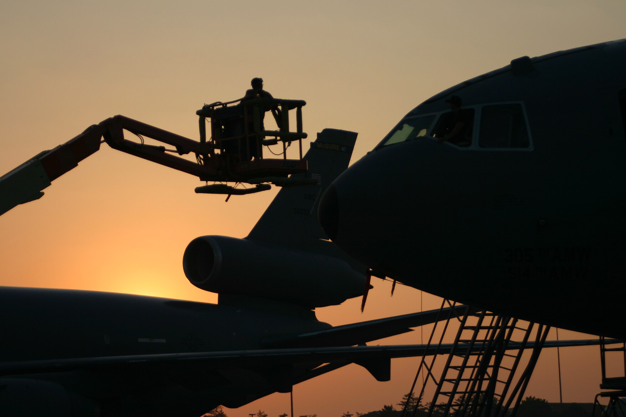 Airmen perform routine maintenance on a KC-10A Extender as the sun rises at McGuire June 10. McGuire Airmen extend America's global reach by generating, mobilizing and deploying 13 C-17 Globemaster III and 32 KC-10 Extender aircraft to conduct strategic airlift and air refueling missions. The base's aircraft have participated in nearly every important military contingency from 1994 to today, including Operations Northern and Southern Watch, Allied Force, Noble Eagle, Enduring Freedom and Iraqi Freedom. (U.S. Air Force photo/Senior Airman Danielle Johnson)