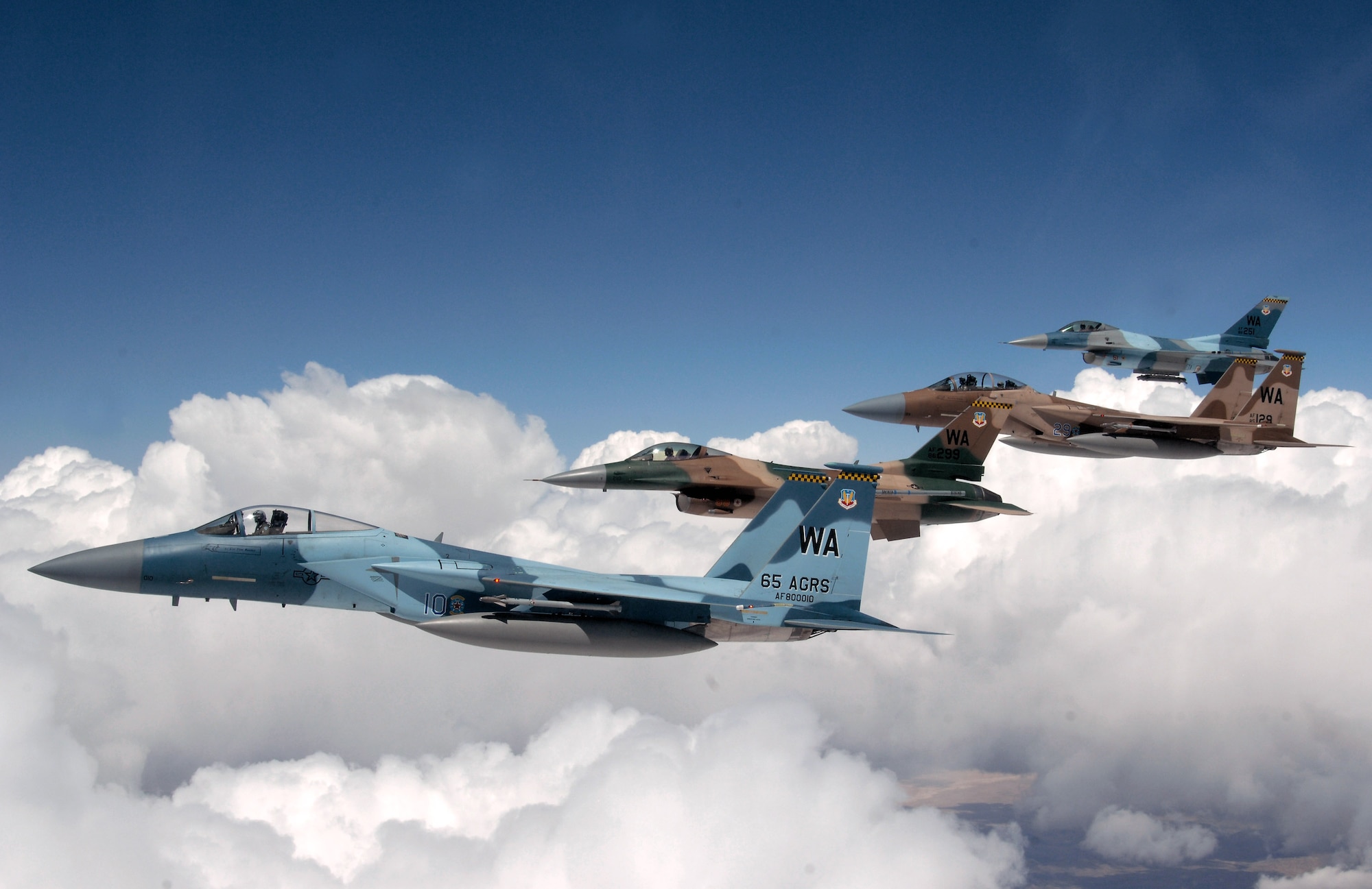 A flight of Aggressor F-15 Eagles and F-16 Fighting Falcons fly in formation June 5 over the Nevada Test and Training Range. The jets are assigned to the 64th and 65th Aggressor squadrons at Nellis Air Force Base, Nev. The Aggressor mission is to prepare the combat air forces, joint and allied aircrews for tomorrow's victories with challenging and realistic threat replication, training, academics and feedback. Aggressor pilots simulate foreign-made combat aircraft and use actual tactics of air forces worldwide. (U.S. Air Force photo/Master Sgt. Kevin J. Gruenwald) 