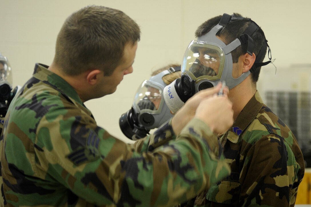 Senior Airman Kristopher Garner (left), 28th Civil Engineer Squadron chemical war fare instructor, blows a small amount of stanic chloride gas around Air Force Cadet Givanni Mikel’s gas mask (right) during a chemical, biological, radiological, nuclear and high-yield explosives training course. This training showed the cadets how effective gas masks are when properly sealed. (U.S. Air Force photo/Airman 1st Class Kasey Zickmund)