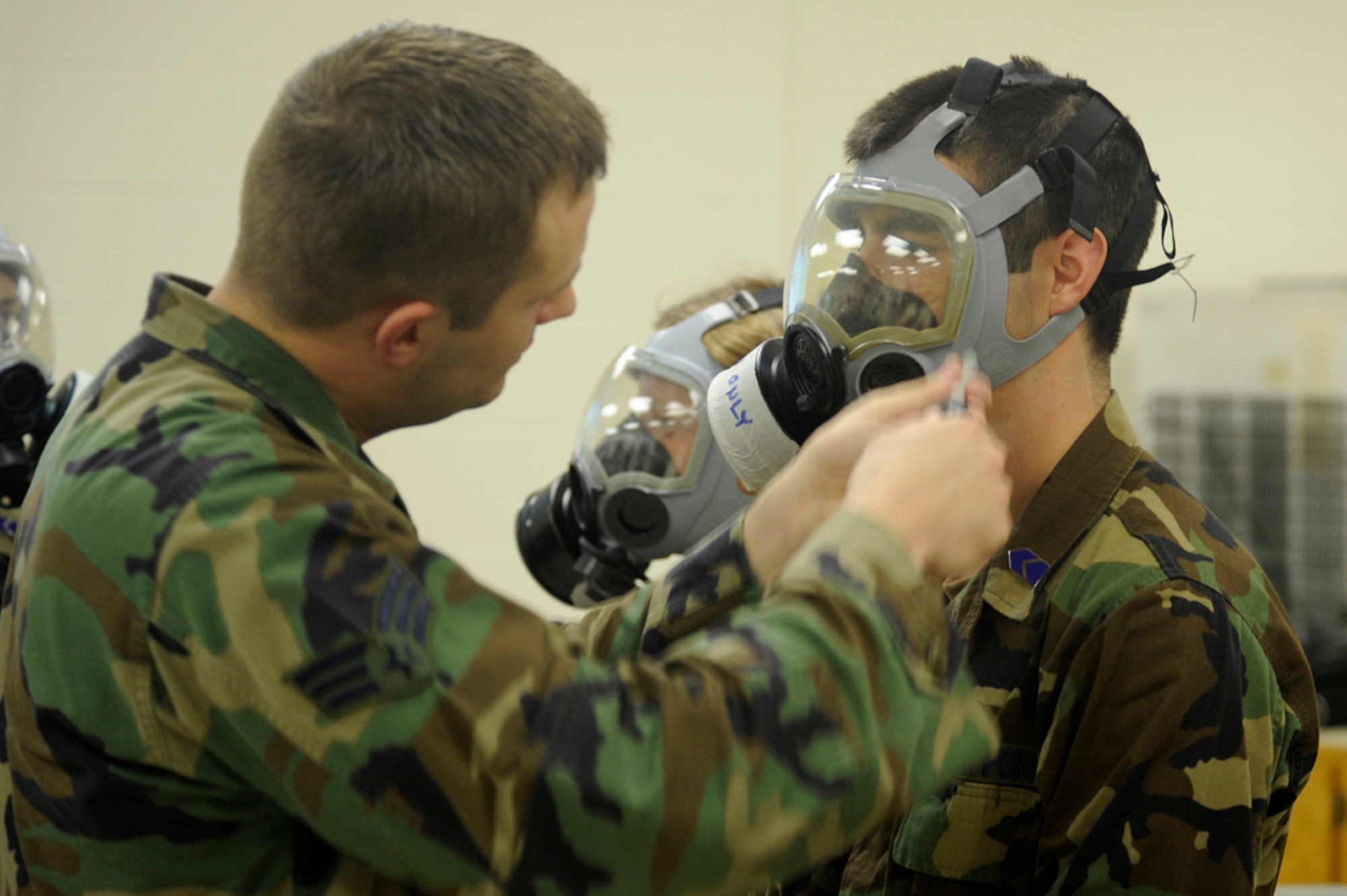 Senior Airman Kristopher Garner (left), 28th Civil Engineer Squadron chemical war fare instructor, blows a small amount of stanic chloride gas around Air Force Cadet Givanni Mikel’s gas mask (right) during a chemical, biological, radiological, nuclear and high-yield explosives training course. This training showed the cadets how effective gas masks are when properly sealed. (U.S. Air Force photo/Airman 1st Class Kasey Zickmund)