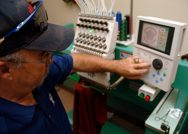 Jacques Cayer programs the automated embroidery machine to stitch a 437th Security Forces badge onto a shirt at 10:30 a.m., 1430 ZULU, at the Arts and Crafts Center at Charleston AFB June 4. Mr. Cayer is the Arts and Crafts Center's embroidery operator and maintainer. (U.S. Air Force photo/Airman 1st Class Timothy Taylor)