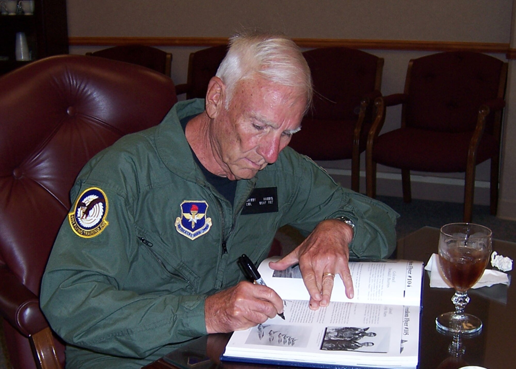 Retired Col. Carlyle "Smitty" Harris signs a book during his visit to Columbus AFB June 6. Colonel Harris was the keynote speaker for the graduation for Specialized Undergraduate Pilot Training class 08-10. Also during his visit, he was able to take a flight in the T-6 Texan II. (U.S. Air Force photo by Sonic Johnson)