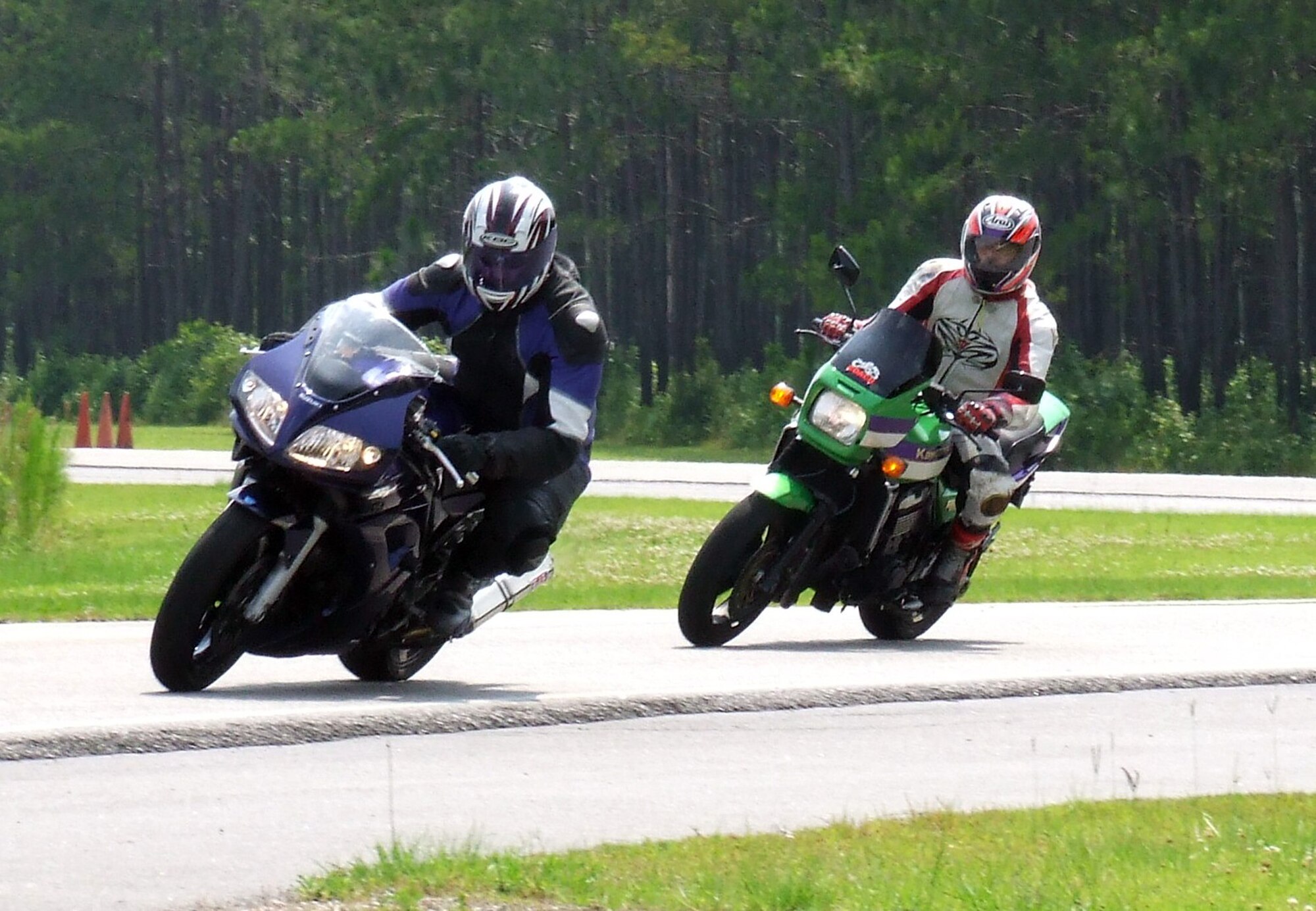Jeff Phipps looks through one of the corners on a motorcycle training course as Kenny Roberts evaluates his positioning and speed during field testing of a new motorcycle training program June 4 at the Federal Law Enforcement Training Center's  Emergency Vehicle Operations Course track. The new Charleston AFB Motorcycle Operations Course will provide riders with the skills necessary to survive and enjoy the motorcycling experience. Mr. Phipps is a retired master sergeant and Mr. Roberts is a professional motorcycle rider and both volunteer to teach motorcycle safety courses for the base. (U.S. Air Force photo/Master Sgt. Frank Endaya)
