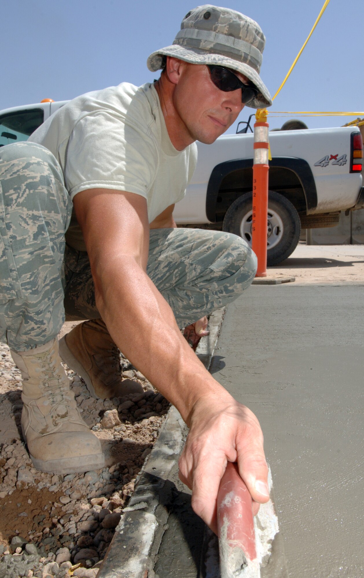 BALAD AIR BASE, Iraq -- Tech. Sgt. Adam Brothers, 332nd Expeditionary Civil Engineer Squadron heavy equipment operator, contours a new sidewalk here, June 10. Sidewalk repair is being accomplished throughout the base housing area to eliminate tripping hazards. Sergeant Brothers is a deployed from Patrick Air Force Base, Fla.  (U.S. Air Force photo/ Master Sergeant Heather Cabral)