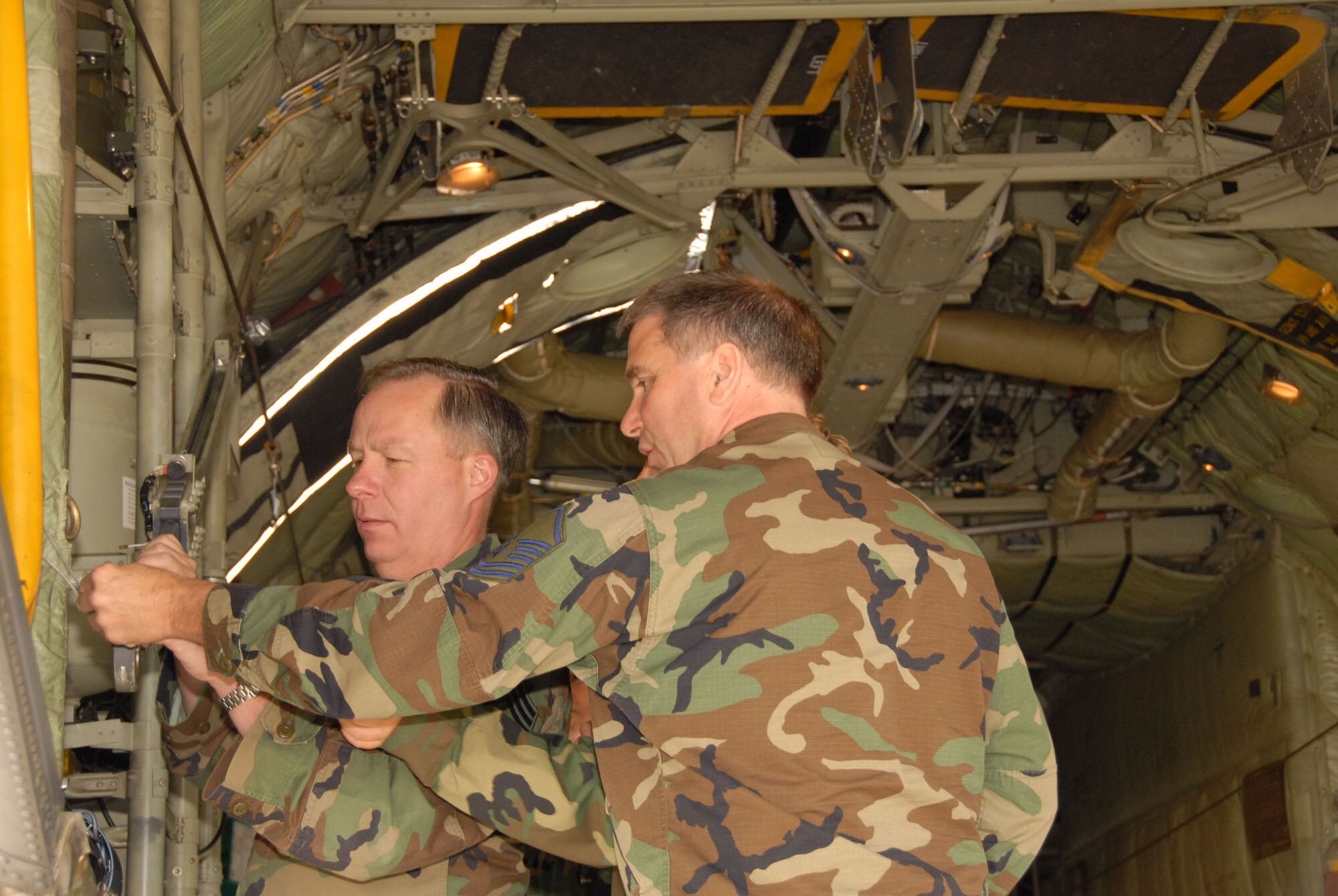 Chief Master Sgt. Phillip Tavenier and Master Sgt. William Davis adjust the cargo door on the C-130 during their feild training class. The 107th is converting from the KC-135R to the C-130H2. (U.S. Air Force photo/Senior Master Sgt. Ray Lloyd).