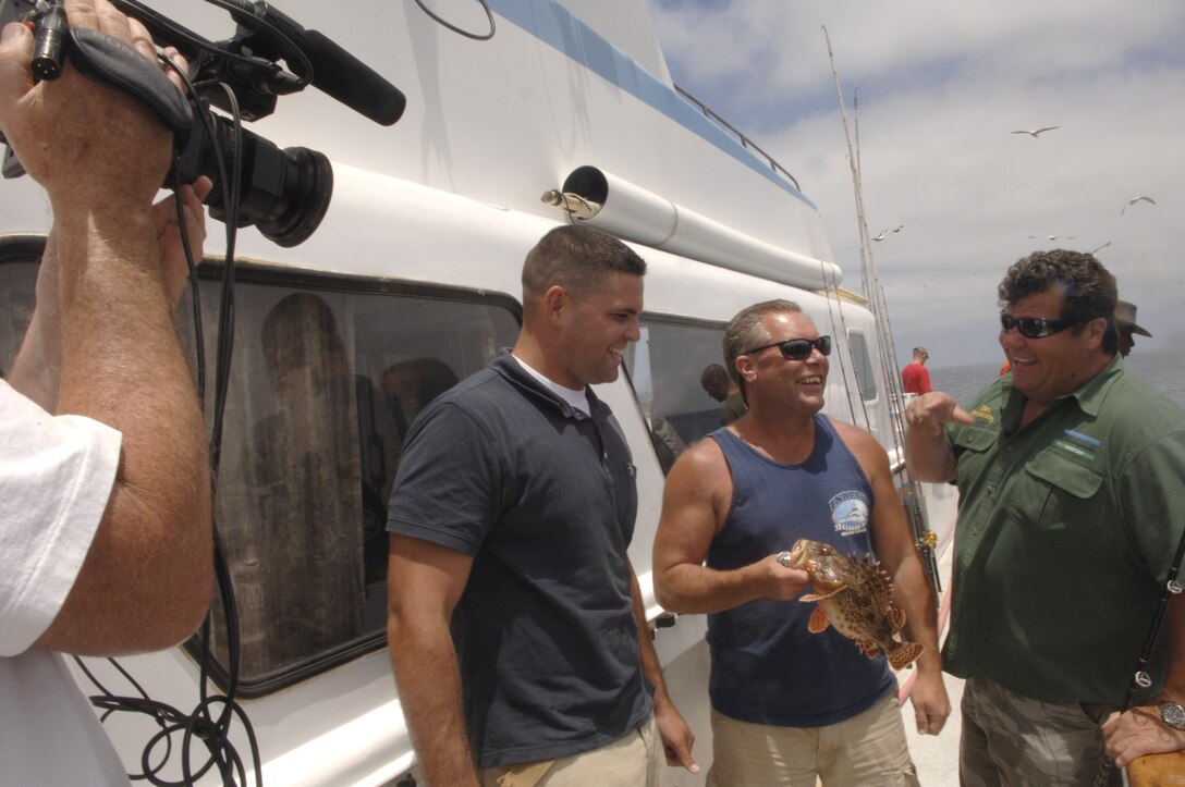 Capt. Richard Fay, operations officer, Recruit Training Regiment, left, and Chris Randell, captain of the Indian , center, are interviewed on the progress of the fishing trip by Dan Hernandez, for his TV show “Sports Fishing with Dan Hernandez.”