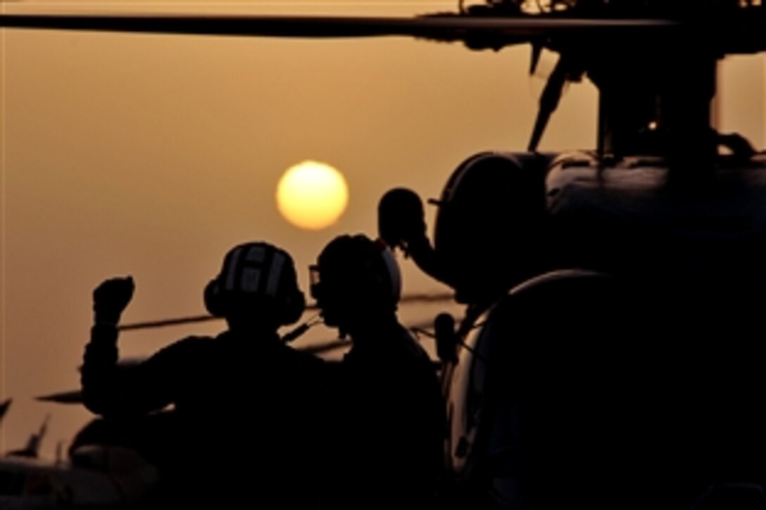 U.S. Navy sailors confer as they prepare to launch an SH-60B Seahawk helicopter from the flight deck of the aircraft carrier USS Abraham Lincoln underway in the Arabian Gulf, June 8, 2008. The USS Lincoln is deployed to the U.S. Navy 5th Fleet area of responsibility to support maritime security operations.