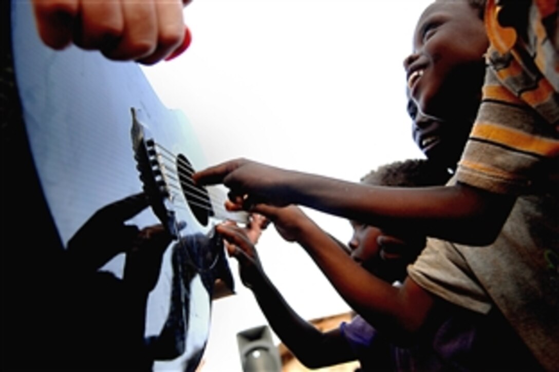 Djiboutian children play with U.S. Air Force Senior Master Sgt. Jimmy Weber’s guitar during a performance by the Air Force Central command band, Falcon, in Negad, Djibouti, May 22, 2008. 