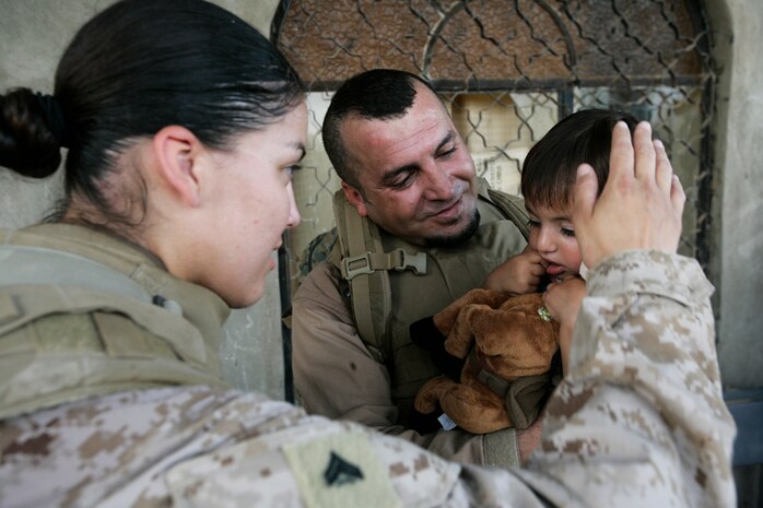 Cpl. Gizelle Gutierrez, left, and an interpreter, center, play with an Iraqi child June 10, 2008. Gutierrez serves with Company G, 2nd Battalion, 3rd Marine Regiment, Regimental Combat Team 1, which is in Al Anbar province conducting patrols and passing out school supplies and toys.