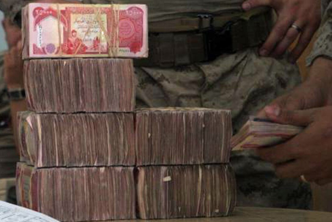 Bundles of Iraqi money are stacked in Rawah, Iraq, June 10 for Hachem Aftan Alsherji, who works for the Al Batra'a company, to count before he officially receives his payment for the contract work he and his company have completed on the bank and courthouse in the city of Rawah. The payments are usually given in installments depending on the size of the project. The courthouse and bank are being refurbished before being turned back over to the local government. The buildings were previously used as a post by Coalition forces. After they were demilitarized, Marines with Civil Affairs Team 5 put together a project to have the buildings repaired so they could once again be used to serve the people of Rawah.