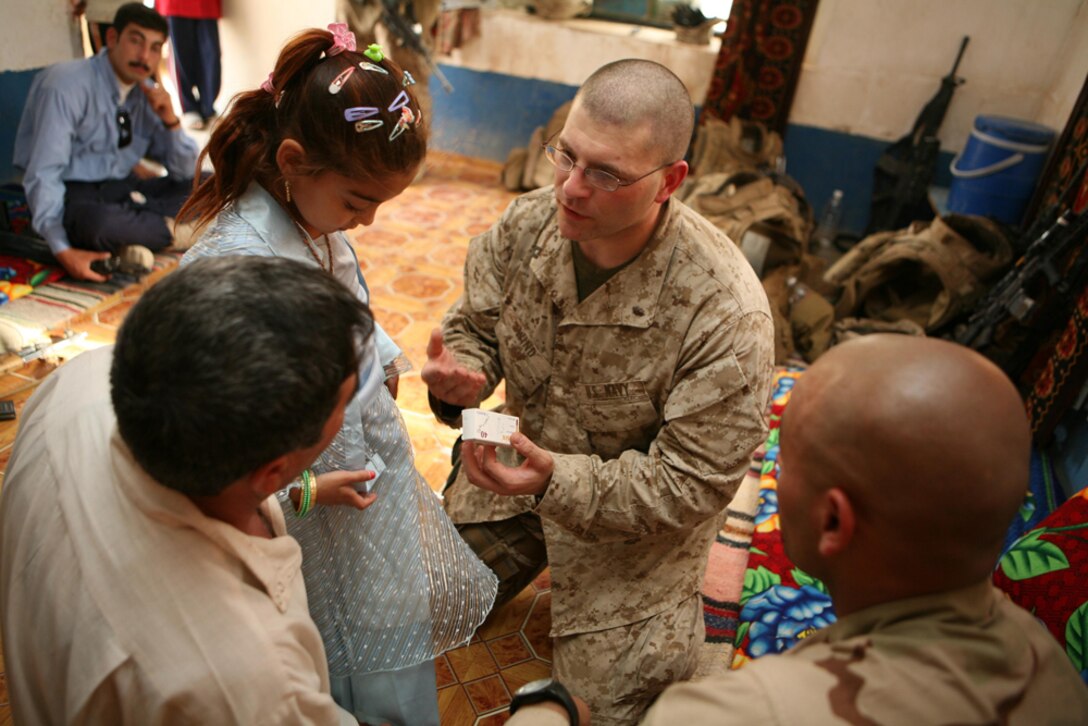 Navy Lt. Benjamin D. Wind, the surgeon with 3rd Battalion, 4th Marine Regiment, Regimental Combat Team 5, explains the importance of a medication to Zalaan Mohsin Rafea at Zalaanâ??s home in Haditha, Iraq, June 12, while his daughter, Basima Zalaan watches.  Basima, 7, recently returned from Jordan after having surgery to correct a congenital heart surgery. Marines with 3rd Bn., 4th Marines, assisted in getting Basima treatment for the heart defect. Zalaan and Basima were all smiles during the visit.
