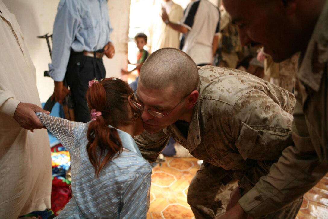 Navy Lt. Benjamin D. Wind, the surgeon for 3rd Battalion, 4th Marine Regiment, Regimental Combat Team 5, bends over to receive a kiss good-bye from Basima Zalaan at Basimaâ??s home in Haditha, Iraq, June 12. Basima, 7, recently returned home from Jordan after heart surgery to correct a congenital defect. She is the third child in the area to receive the surgery, but the first to not go to the United States for the surgery.