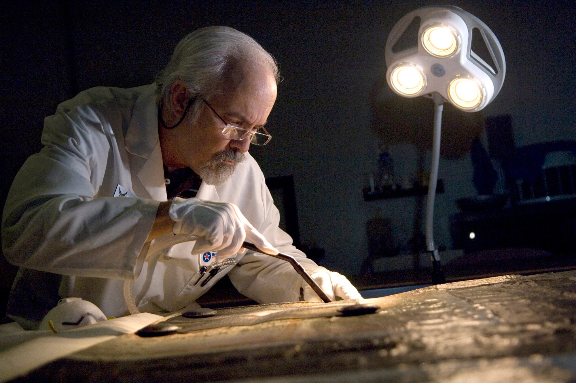 Bob Adair vacuums mold spores and loose abrasive debri on a piece of 90-year-old fabric from a German plane that was recovered. Mr. Adair is a restoration specialist who preserves historic Air Force artifacts in the Restoration Division of the National Museum of the United States Air Force at Wright-Patterson AFB, Ohio. It is the world's largest and oldest military aviation museum featuring 400 aerospace vehicles on more than 17 acres of indoor exhibit space. (U.S. Air Force photo/Master Sgt. Cecilio Ricardo)