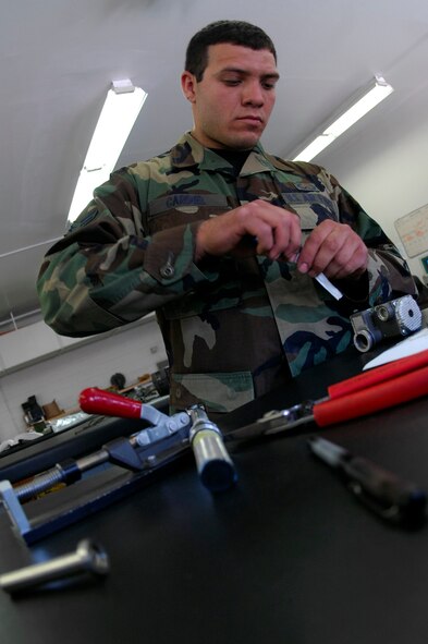 BARKSDALE AIR FORCE BASE, La. - Airman Joe Cardiel of 2d Operational Support Squadron removes a component from a back style parachute before repacking it, June 11. Members of Life Support and Survival Equipment recently merged to form one unit called Aircrew Flight Equipment. (U.S. Air Force photo by Airman 1st Class Joanna M. Kresge)