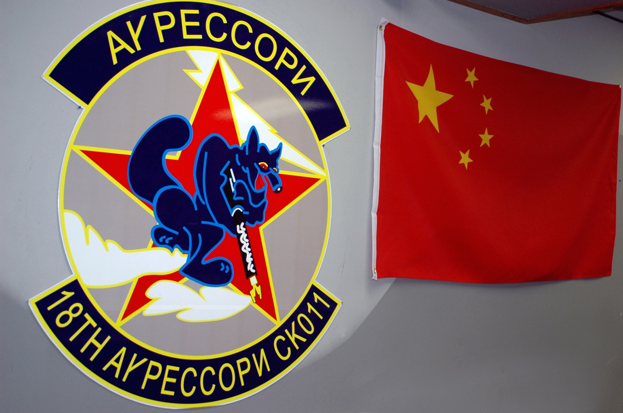 Pilots of the 18th Aggressor Squadron immerse themselves with items such as their unit patch in Russian and the Chinese Flag to think in the mindset of other nations.  This helps them in Red-Flag Alaska where they replicate the "threat" in an exercise designed to provide aircrew training to increase their chances of survival in combat environments.  (U.S. Air Force photo by Airman 1st Class Nora Anton)