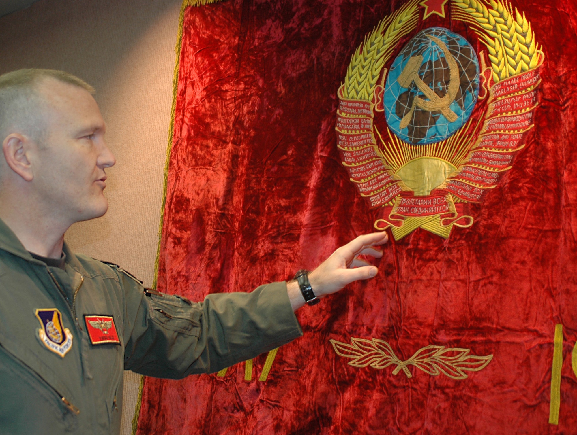 Capt. Todd "Borus" Hale, 18th Aggressor Squadron pilot, shows an authentic USSR flag that he obtained during the two years he spent in Russia as a missionary. The flag is on a wall at 18th AGRS where it lends to the ambience pilots created to place themselves in the "enemy" mindset for Red-Flag Alaska. The 18th AGRS chose the pretense of the Soviet Union to emulate since they represented a past threat.  (U.S. Air Force photo by Airman 1st Class Nora Anton)