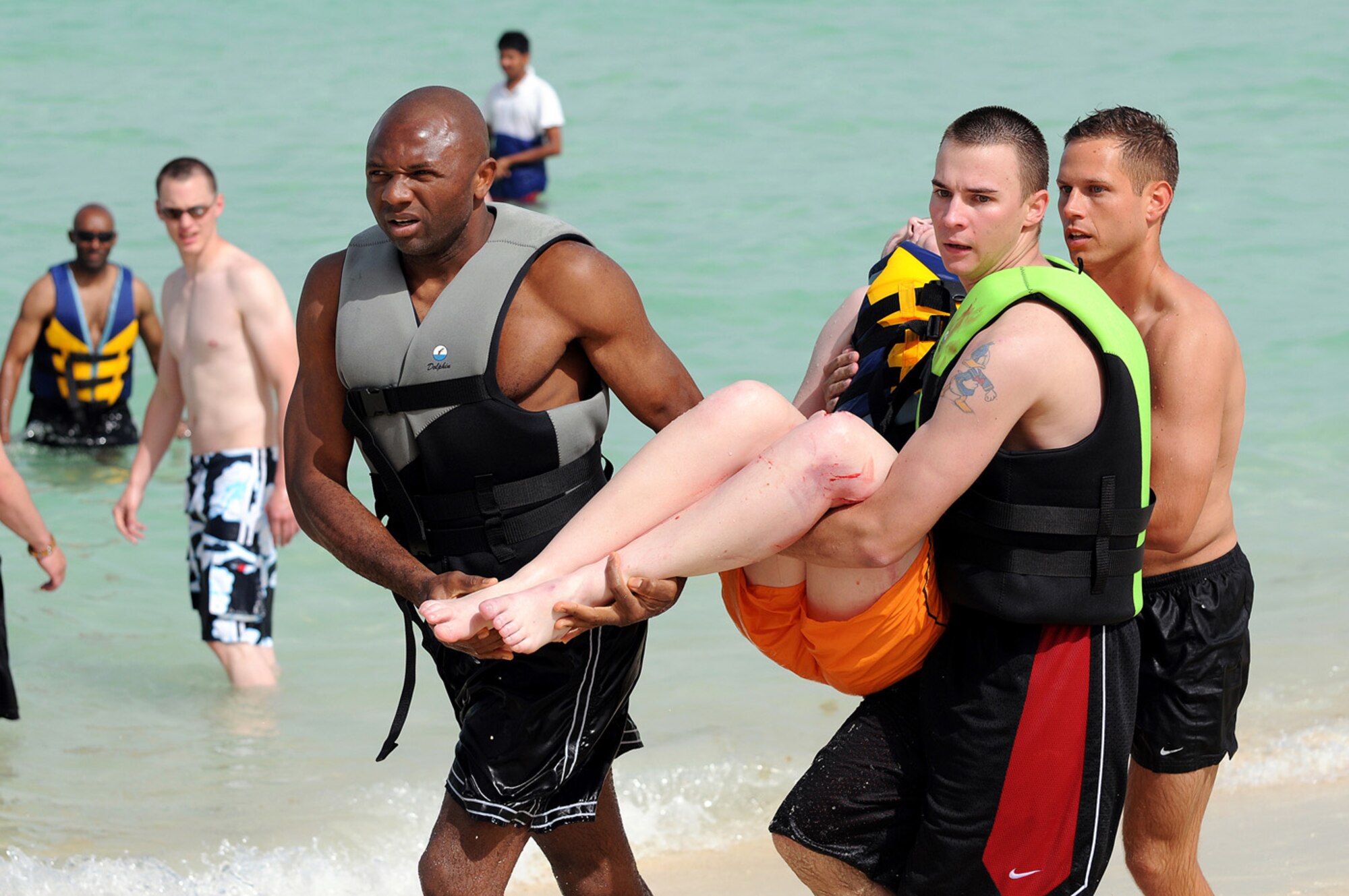 Senior Airman Bruce Scheel Jr., in the middle, carries Army 2nd Lt. Elizabeth Sutey to an ambulance on a beach in a deployed environment. Airman Scheel’s actions saved Lieutenant Sutey’s life (Courtesy photo).