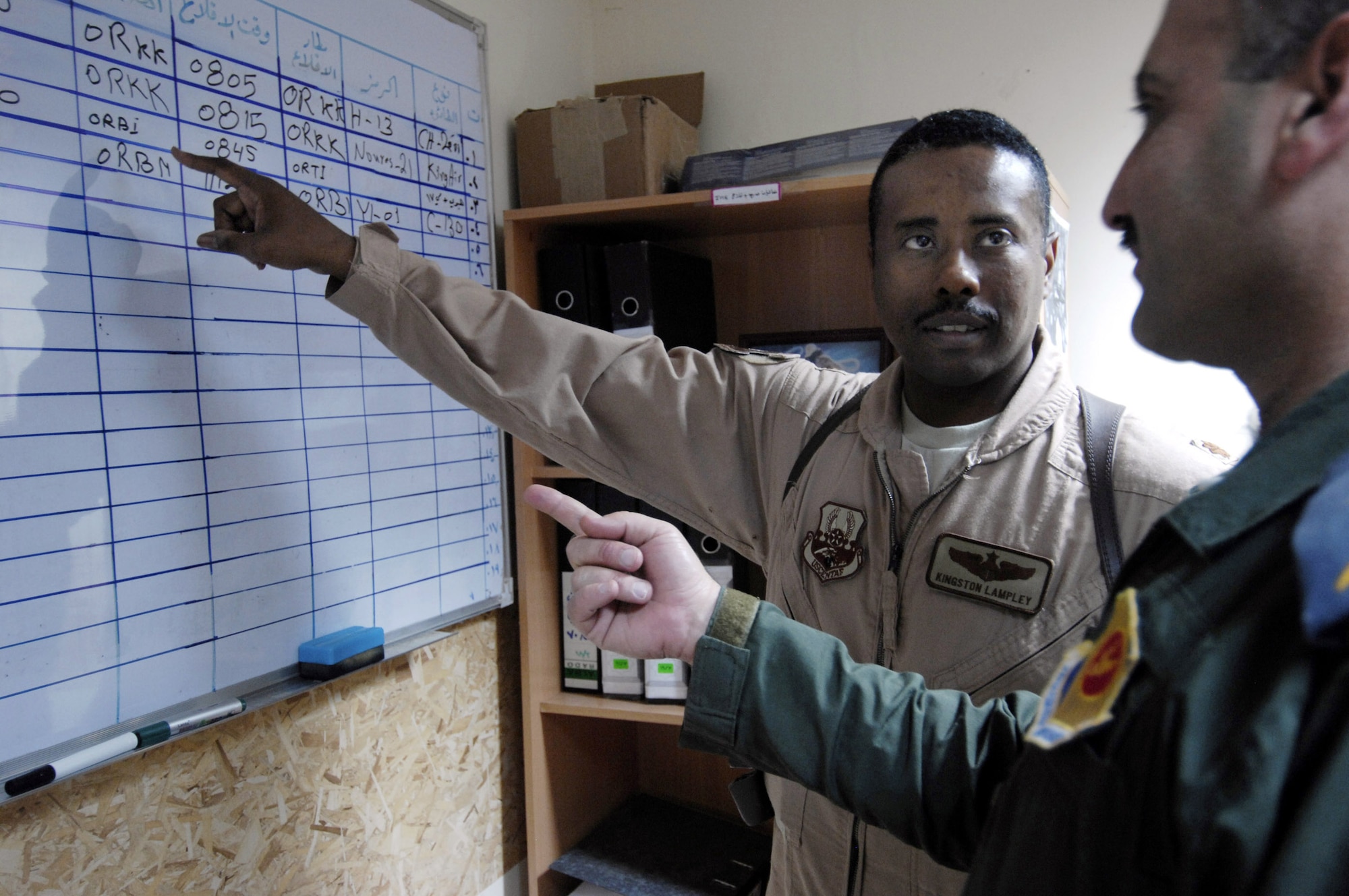 Maj. Kingston Lampley advises an Iraqi air operations center officer about proper flight schedules at the Iraqi Air Operations Center at Camp Victory, Iraq, May 28. Major Lampley is a military transition team member, advising Iraqi officers concerning the day-to-day operations in their air operations center. The Iraqi AOC is run completely by Iraqi military officers and advised by Air Force military transition team officers. The AOC MTT is responsible for teaching and preparing the Iraqi military to take over AOC operations independent from the U.S. military. (U.S. Air Force photo/Staff Sgt. Christina M. Styer)
